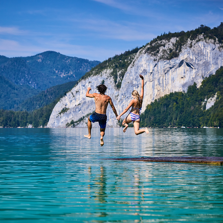 Ein Junge und ein Mädchen die in den See springen