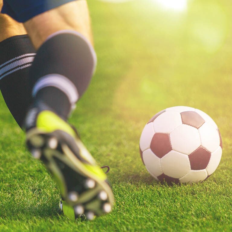 Zu sehen ist ein Spieler der den Fußball schießt