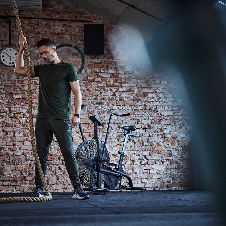 Ein Mann der mit einem dickeren Seil im Fitnessstudio trainiert