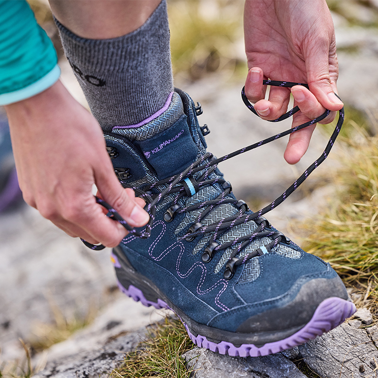 Eine Person schnürrt ihre Wanderschuhe