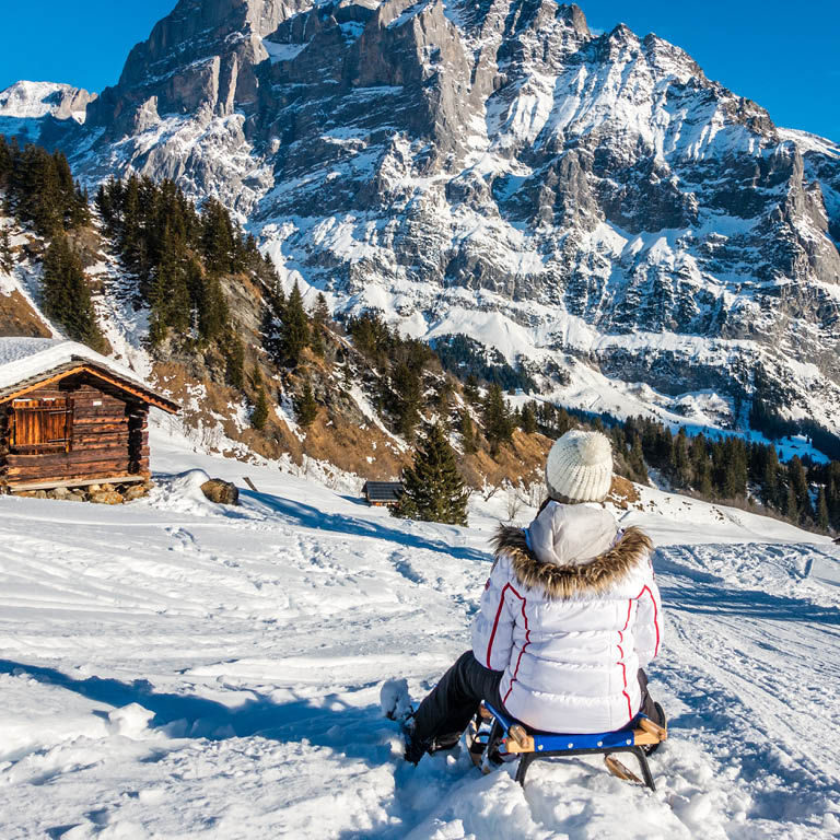 Eine Frau fährt auf einer Rodel den Berg hinunter im Schnee