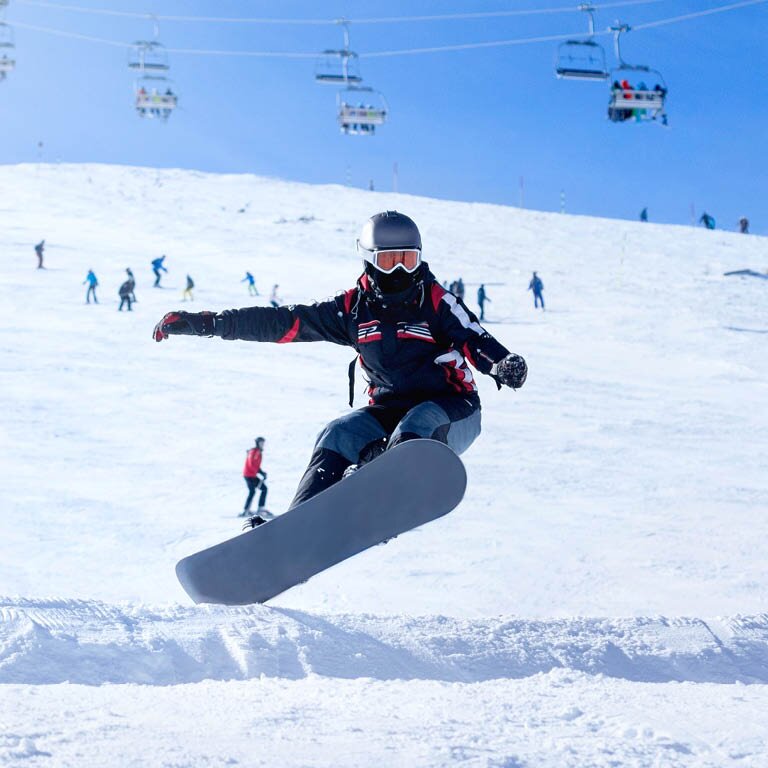Eine Person die mit dem Snowboard über eine Rampe springt