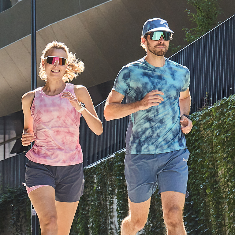 Zwei Personen in Laufbekleidung joggen in der Stadt.