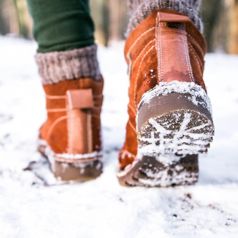 Braune Winterstiefel die durch den Schnee laufen