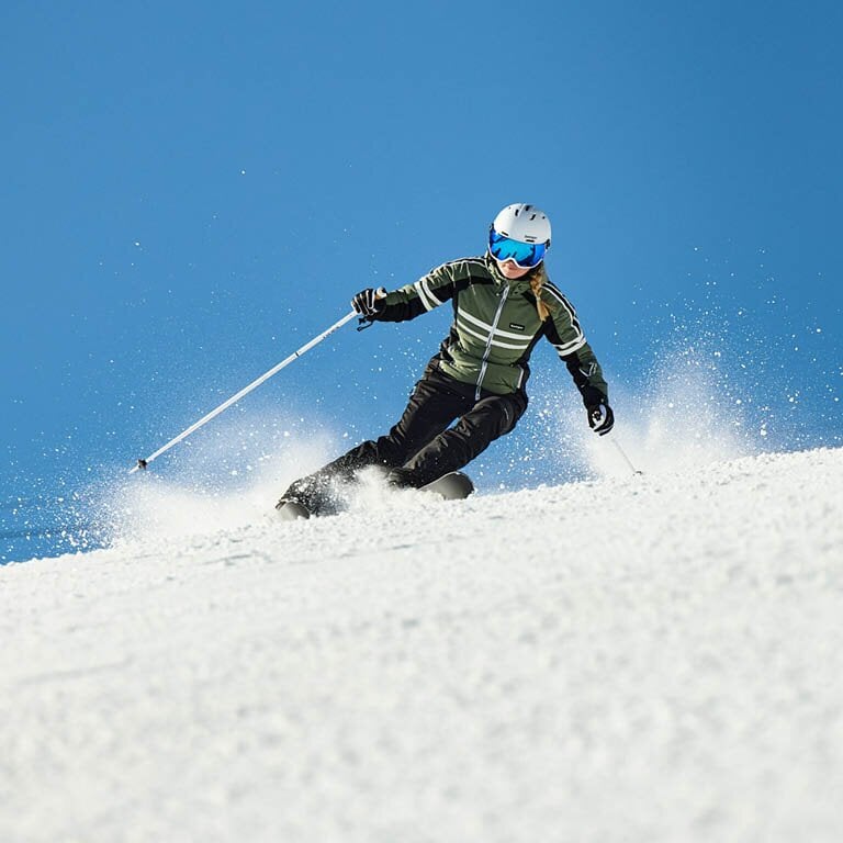 Eine Frau die mit Skiausrüstung über die Piste fährt
