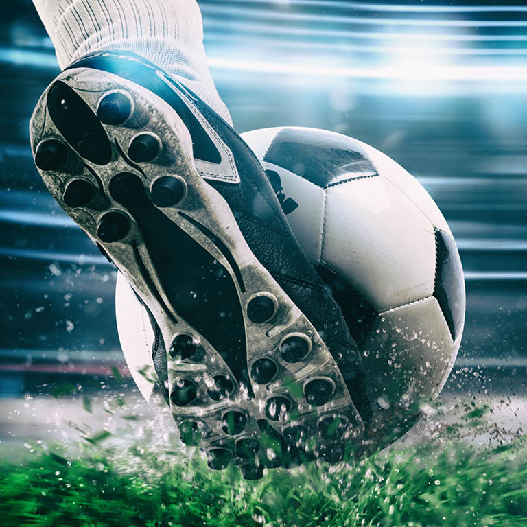 Einen Fuß mit Fußballschuhe, welcher den Ball von einer Linie schießt