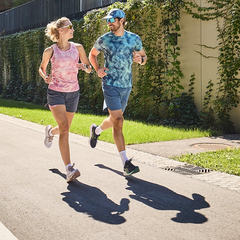 ein Mann und eine Frau laufen lachend auf einer Straße