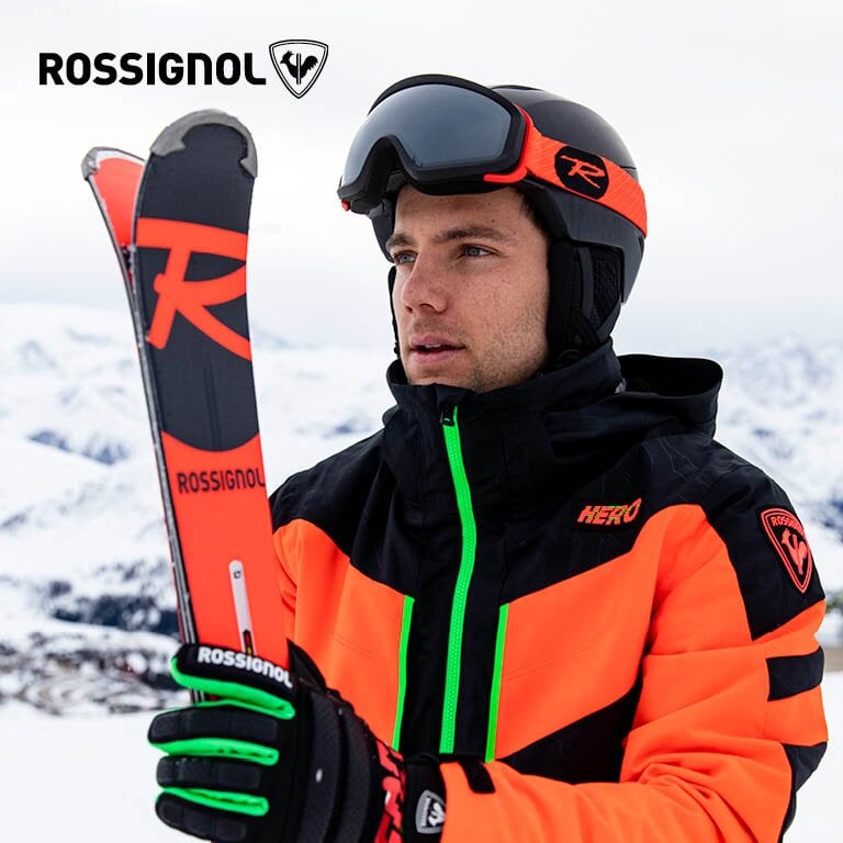 Rossignol  Ein Mann der mit seiner Rossignol Skiausrüstung vor einer Hütte steht