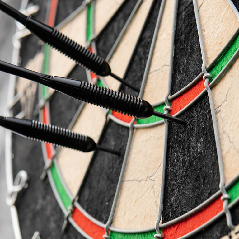 Zu sehen ist eine Dartscheibe mit Pfeilen