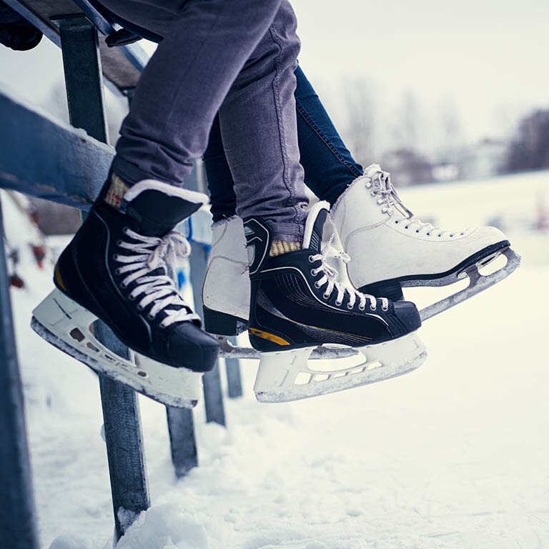 Zu sehen sind zwei Eisluafe Schuhe an einem See in schwarz und weiß.