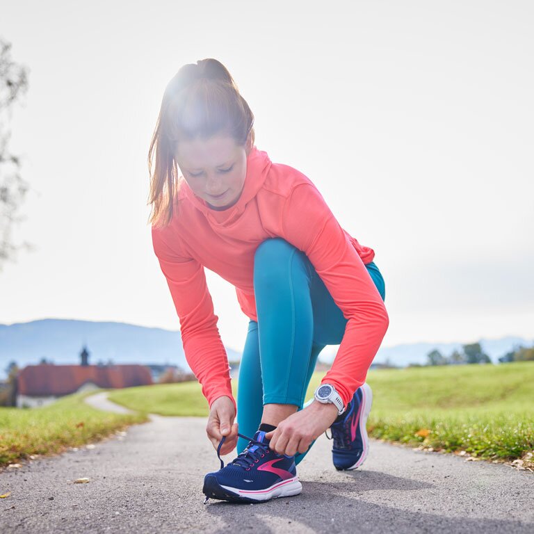Eine Frau die sich ihre Laufschuhe bindet