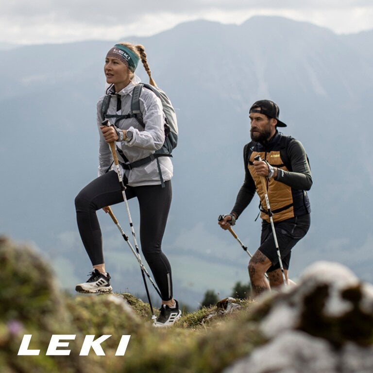 Leki  Eine Frau und ein Mann besteigen einen Berg mit ihren Leki Wanderstöcken