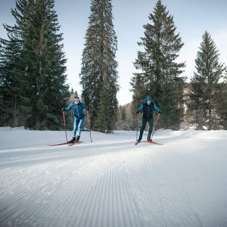 Ein Mann und eien Frau fahren mit ihren Langlaufski über die Piste