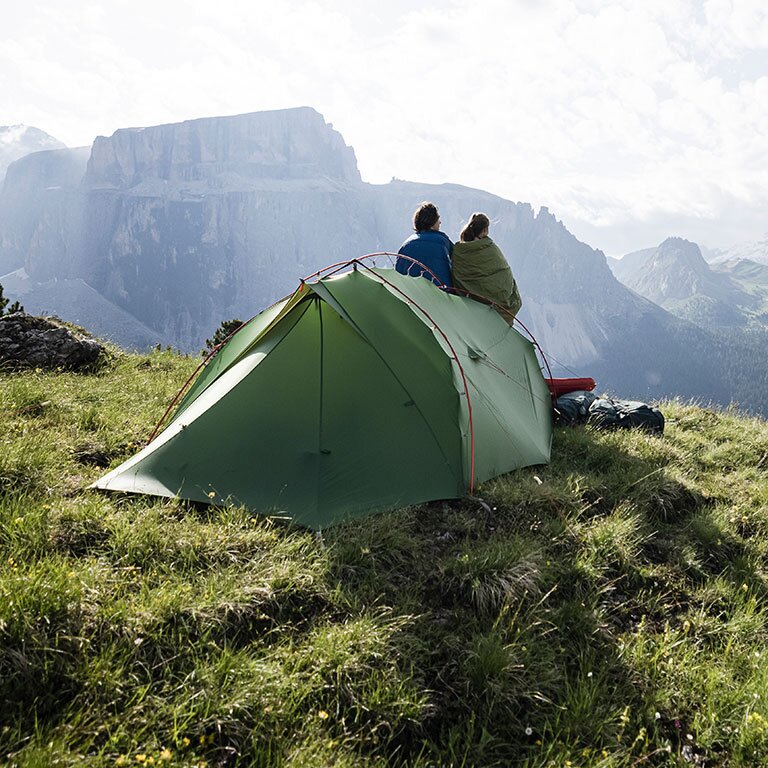 Zu sehen ist ein Zelt was auf einer Wiese in den Bergen steht