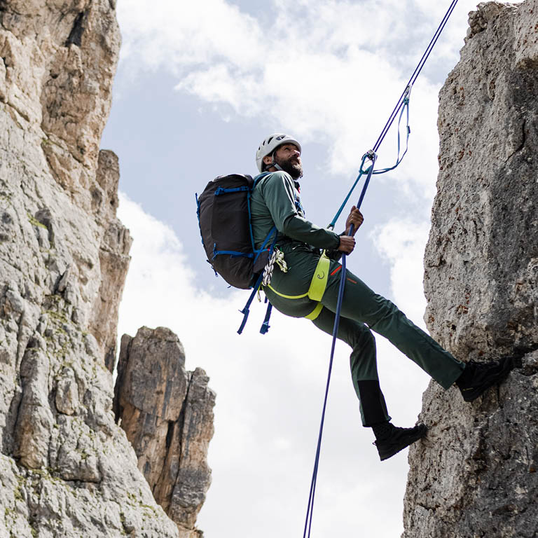 Ein Mann der mit seiner Kletterausrüstung den berg hochklettert