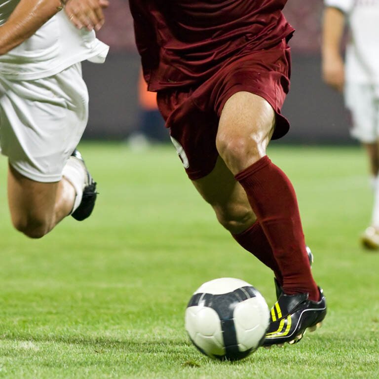 Zwei Personen die um den Ball beim Fußball spielen kämpfen
